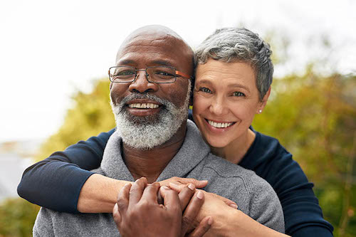 Happy mature interracial couple embracing outdoors with smiles, showing affection and connection in nature