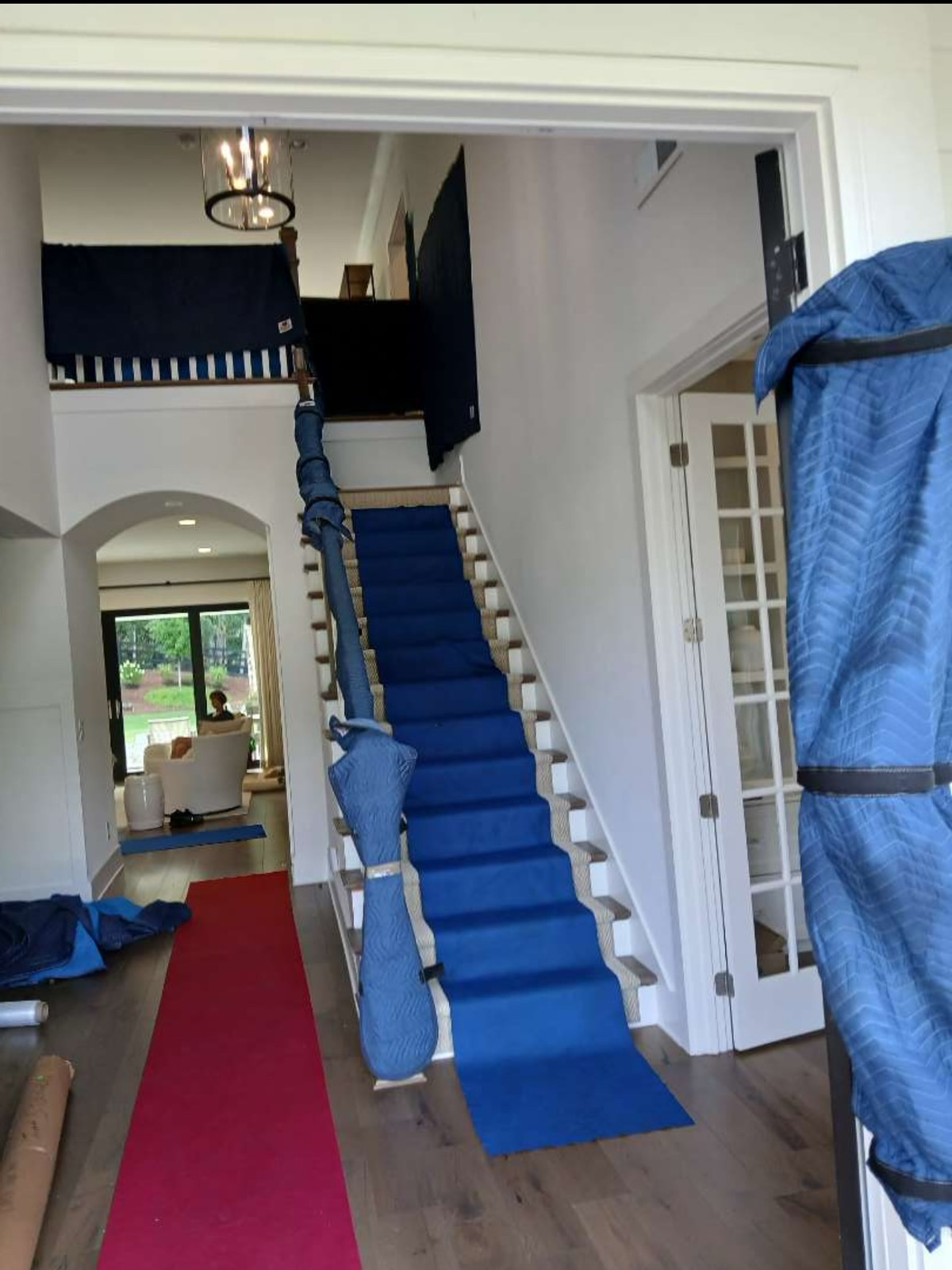 Floor runners laid down a staircase and hallway with padded furniture ready to move