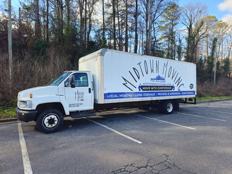 Midtown Moving box truck parked in a lot, with local moving, long distance, packing and unpacking, and junk removal listed on its side