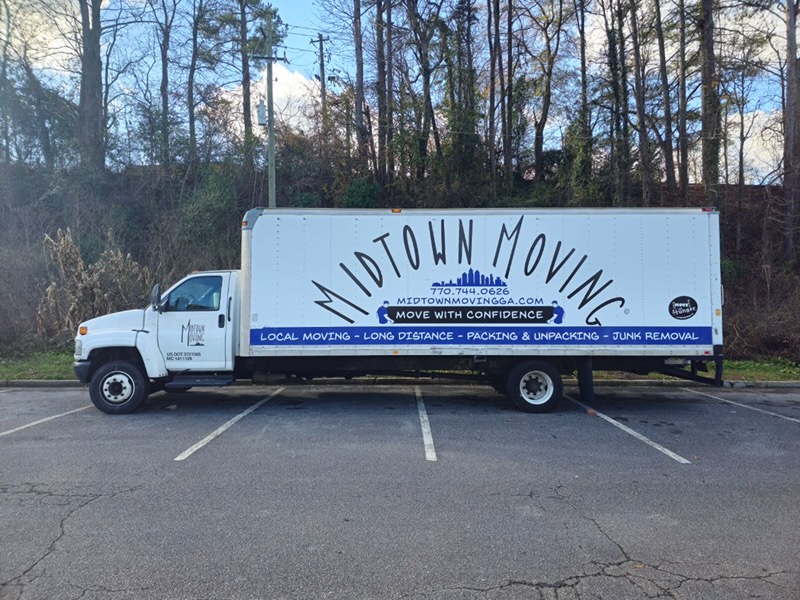 Midtown Moving box truck parked in a lot, with local moving, long distance, packing and unpacking, and junk removal listed on its side
