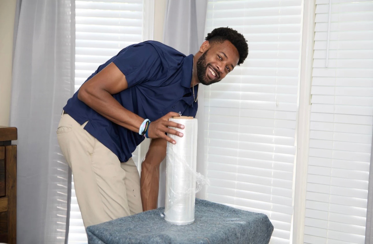 Midtown mover shrink-wrapping furniture inside a room