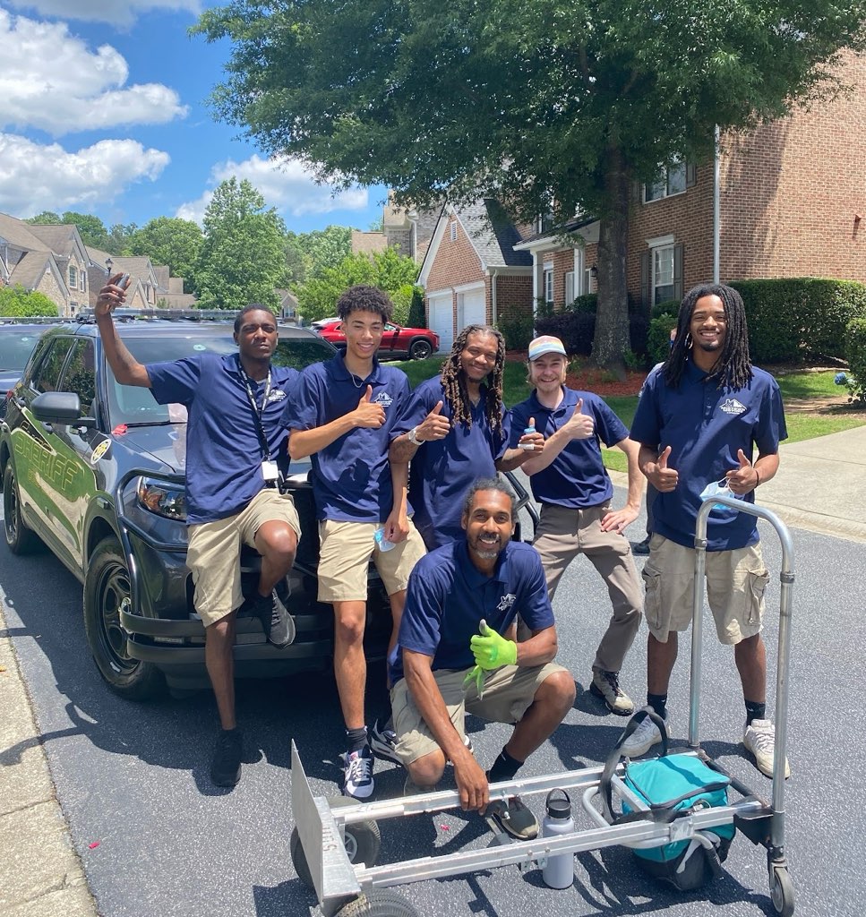 A Midtown Moving crew in uniform giving a thumbs up on a neighborhood street