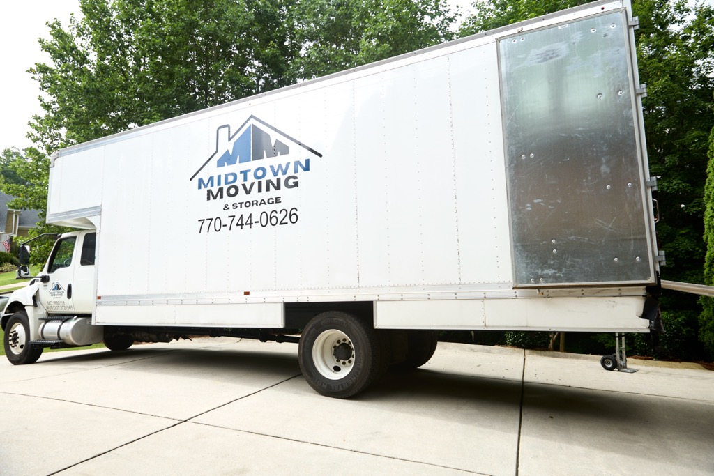 Midtown Moving box truck parked in the driveway of a brick home