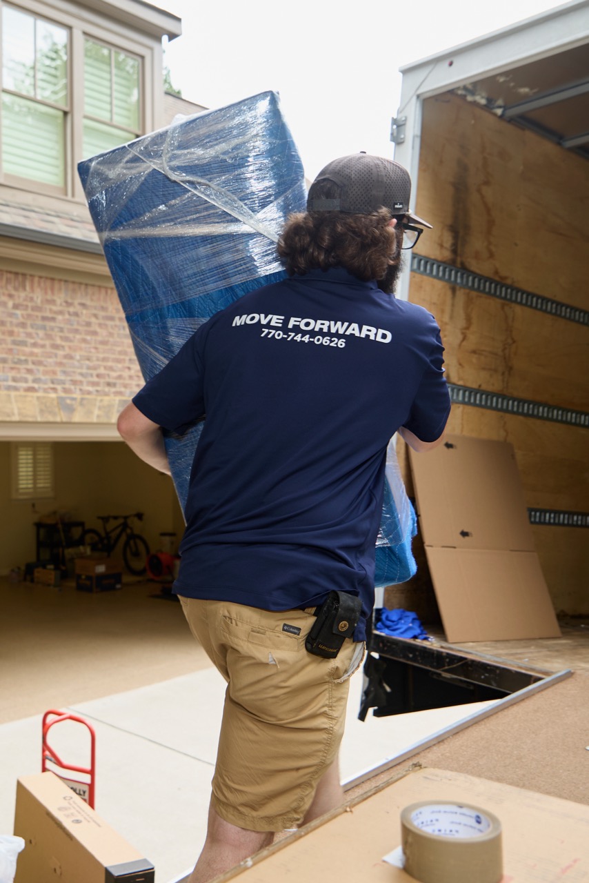 An object wrapped in a moving blanket and shrink wrap, safetly loading it in a truck.