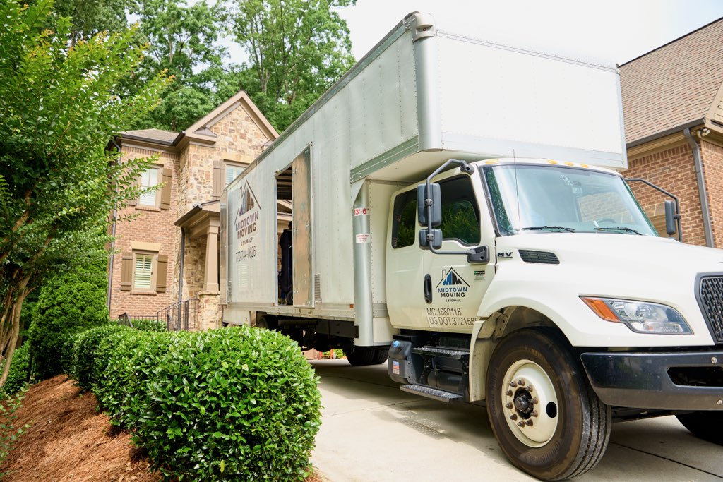 Midtown Moving box truck parked in the driveway of a brick home