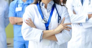 Female doctor with group of happy successful colleagues; blog: Nurse Practitioner vs Physician Assistant: What's the Difference?