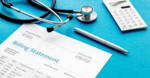 medical treatment bill, calculator and phonendoscope on blue desk background; blog: price transparency in healthcare
