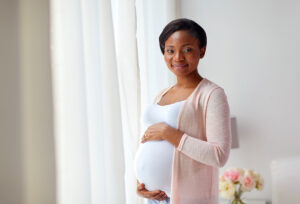 pregnant african american woman at home window