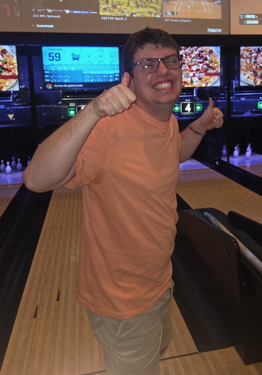 A young man giving a thumbs up at the bowling alley