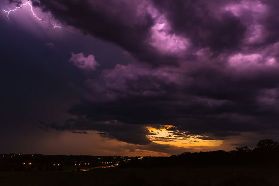 Dark storm clouds roll across a highway at sunset.