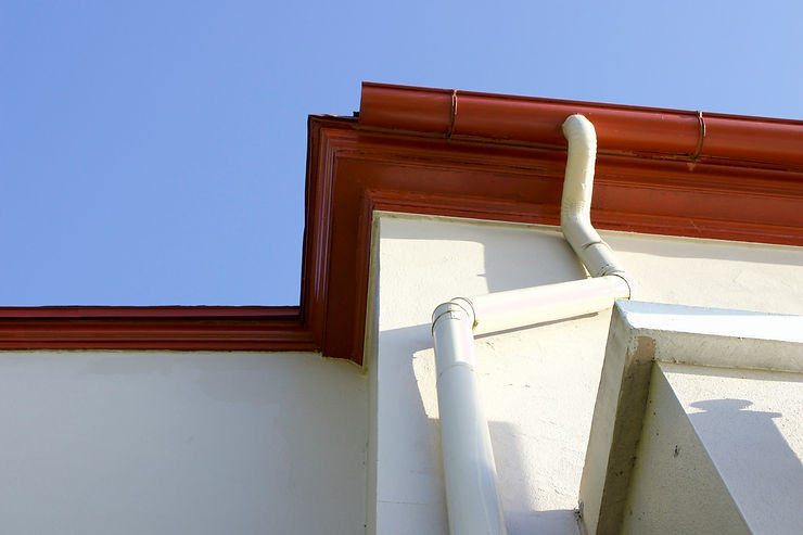 White gutters attached to the underside of a brown roof.