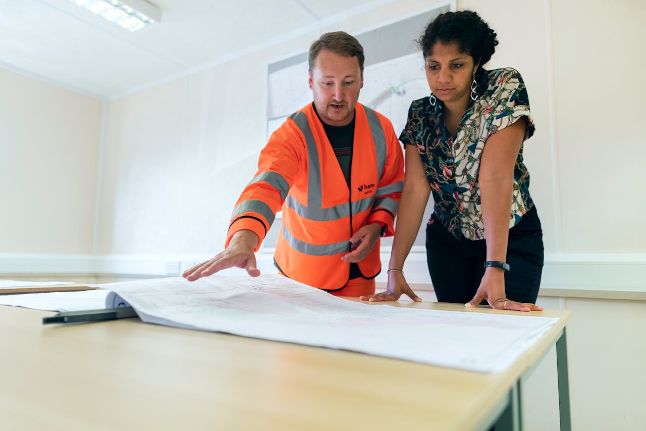 A woman and a construction tradesperson look over plans.